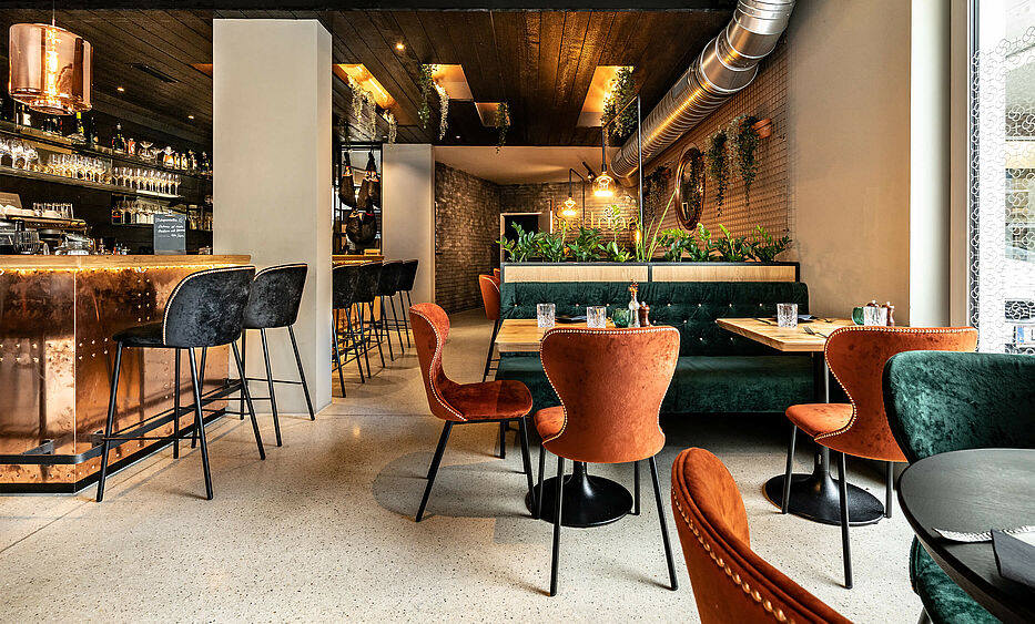 Restaurant Einrichtung von der id Werkstatt, sapnisches Lokal mitten in Linz. Verkohltes Holz kombiniert mit Kupferfronten und samtigen Stoffen. Geschliffener Betonboden und warmes Licht ergeben ein südländisches Flair