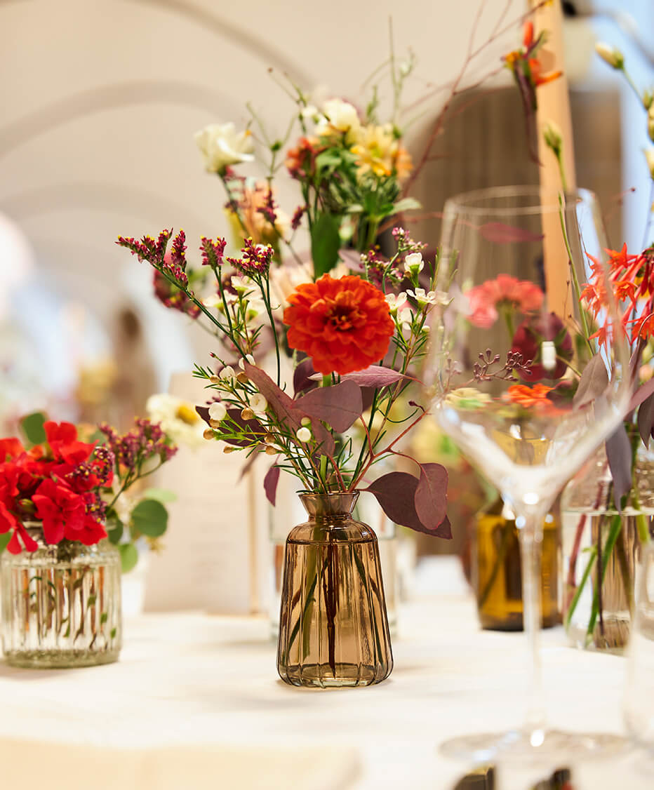 Tischdeko mit Frischen Blumen auf den Runden Tischen im Gewölbesaal der Aula Bernardi