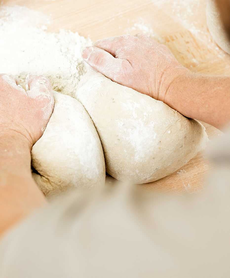 Bäcker Hände bei der Arbeit - Teig wird auf Holzbrett geknetet 