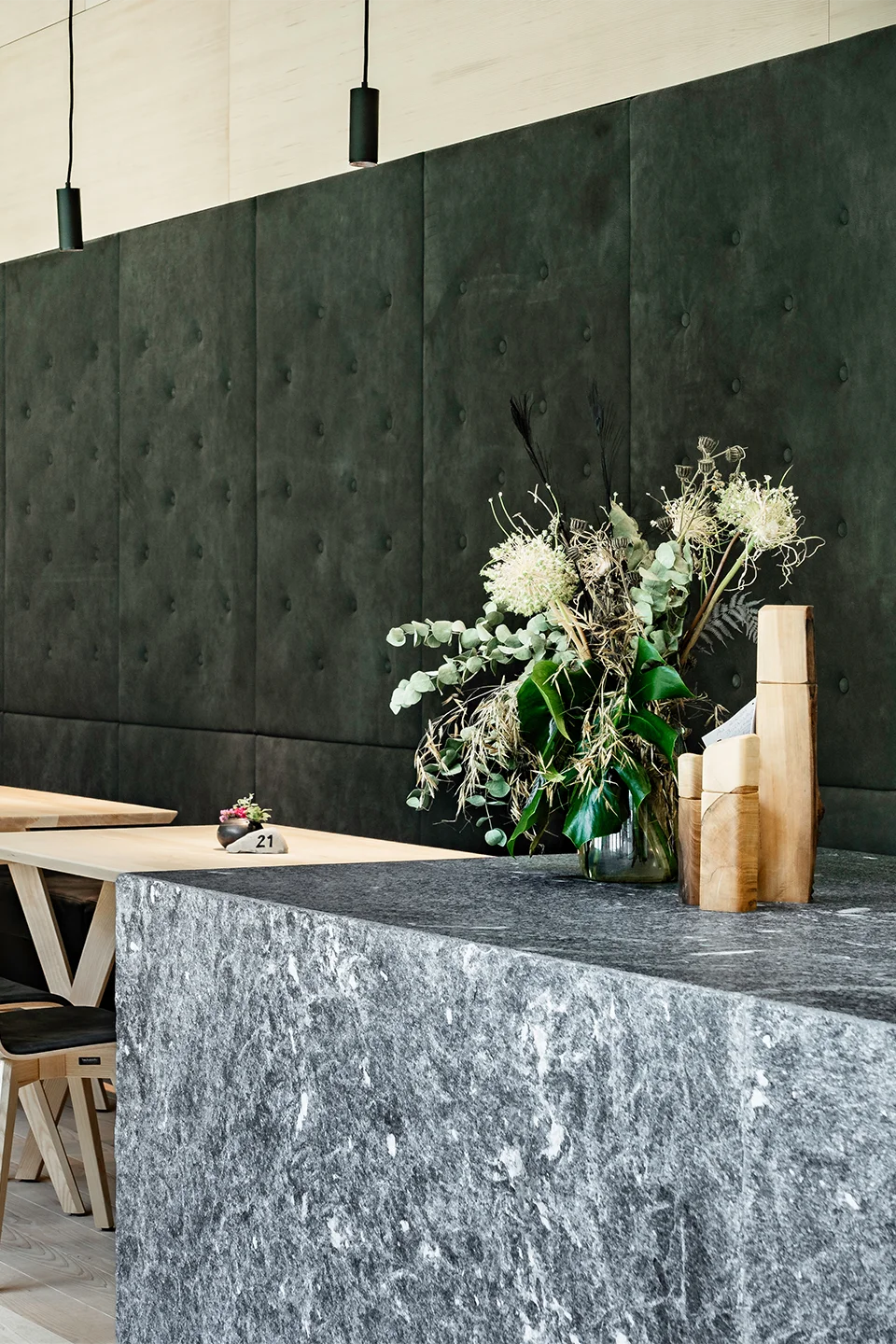 Detail der Granitbar im Fort Kniepass mit großem Wildblumenstrauß, Holzdekoration und dunkelgrüner Wandpolsterung mit Knöpfung