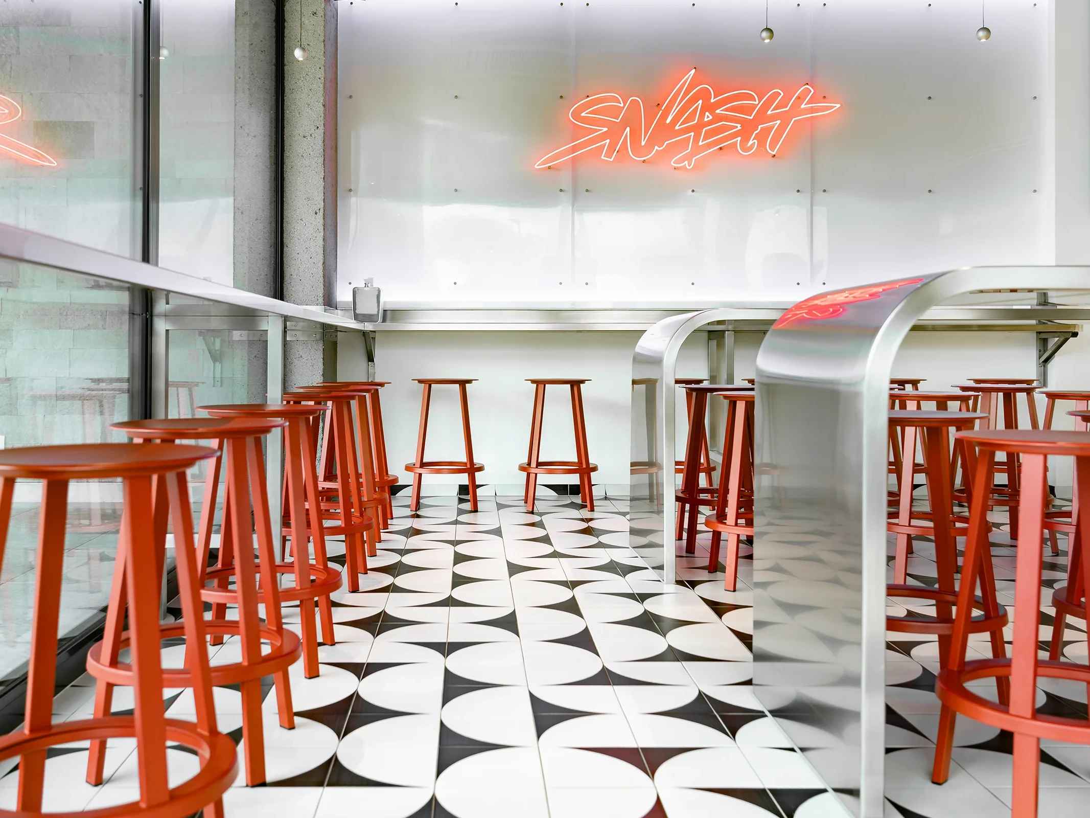 Modernes SB Restaurant in Bürs mit klarer Innenarchitektur, grafischem Fliesenboden, roten Barhockern und offenem Raumkonzept