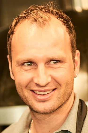 Porträt des lächelnden Geschäftführers vor dem warmen Hintergrund der Restaurantküche