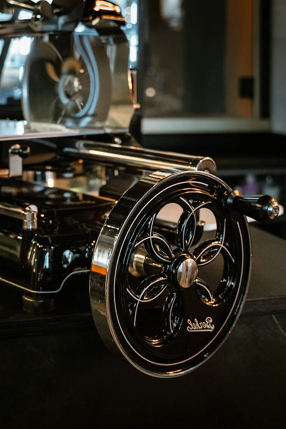 Detailansicht einer vintage Berkel-Aufschnittmaschine mit schwarzem Gussrad und Chromdetails auf dem Marmortresen im Erbario in Schwaz.