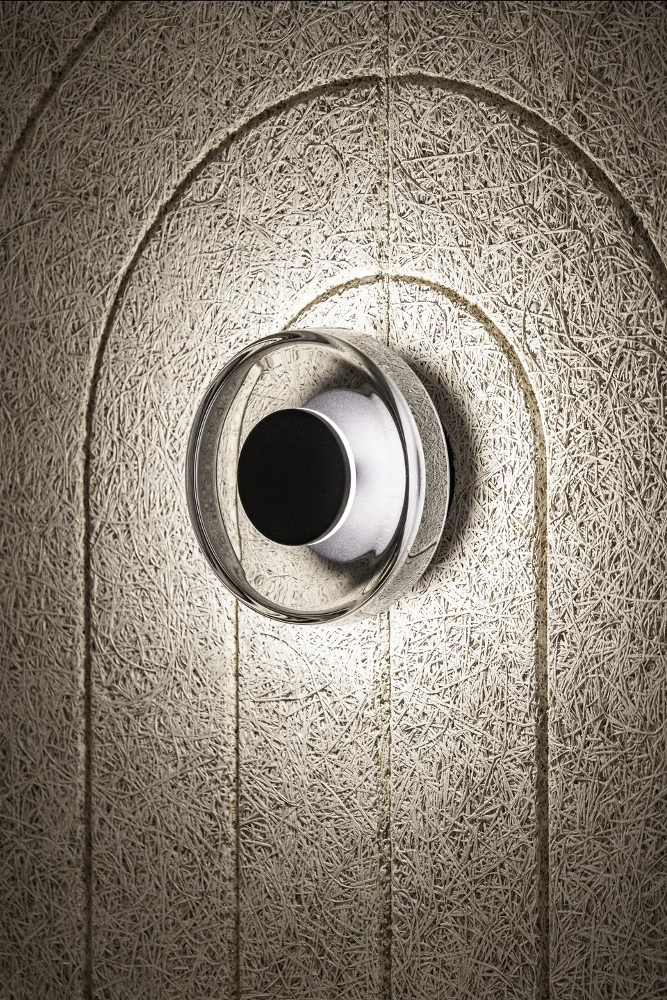 Detail der runden Wandleuchte im strukturierten Bogenrahmen des Hanako Dornbirn.