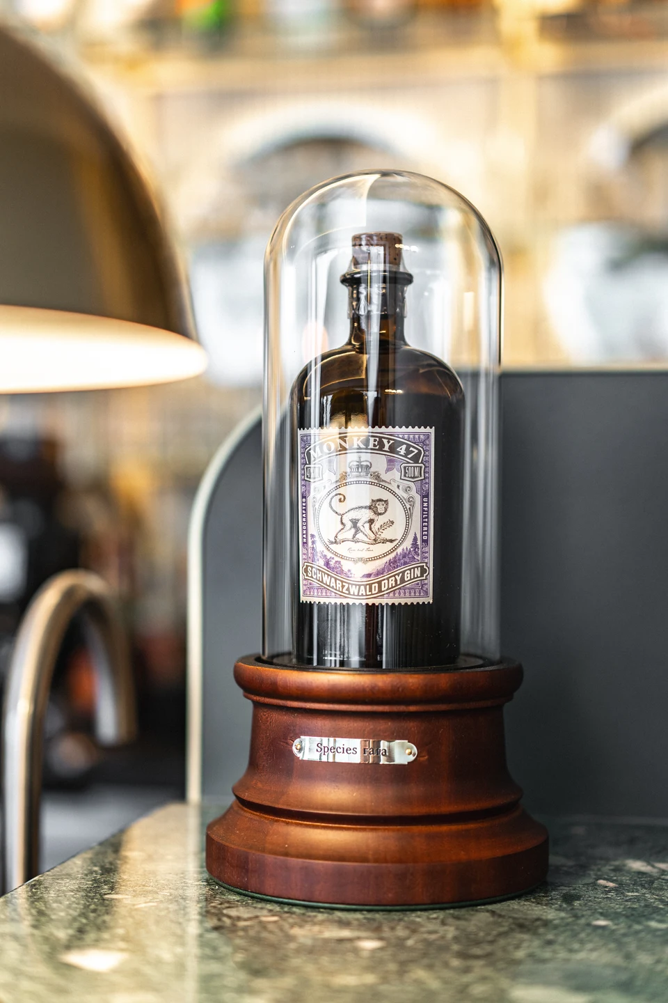 Monkey 47 Schwarzwald Dry Gin-Flasche unter einer Glasglocke auf einem Holzsockel auf dem Marmortresen der Bar Rio in Dornbirn.