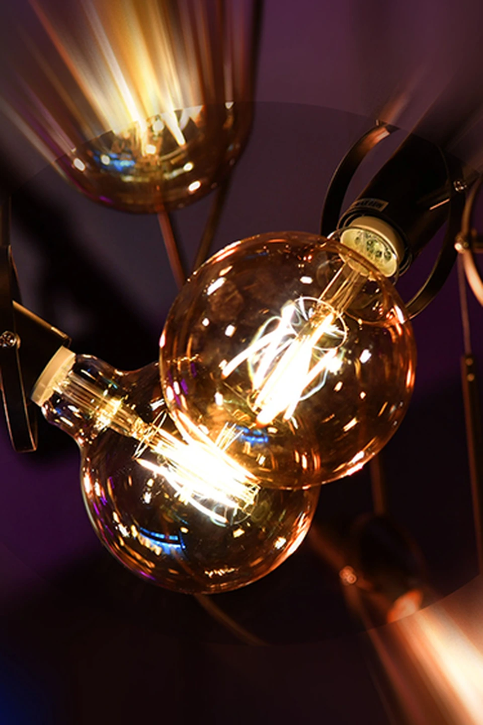 Detailaufnahme von Glühbirnen-Pendelleuchten in Kupferfassung mit warmweißem Licht im Schauspiel.