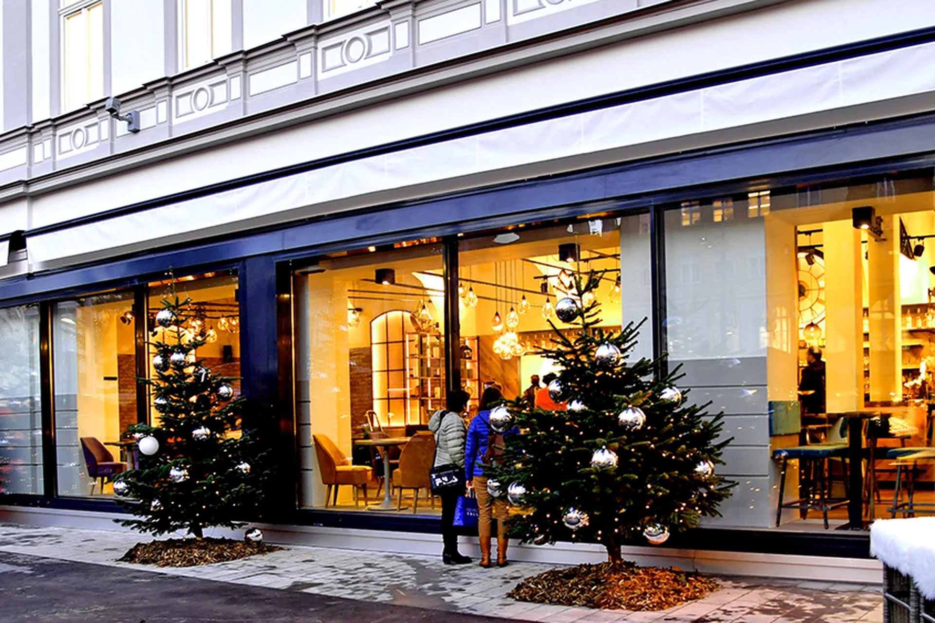 Außenfassade des Schauspiel bei Tageslicht mit großer Schaufensterfront und dekorierten Weihnachtsbäumen.