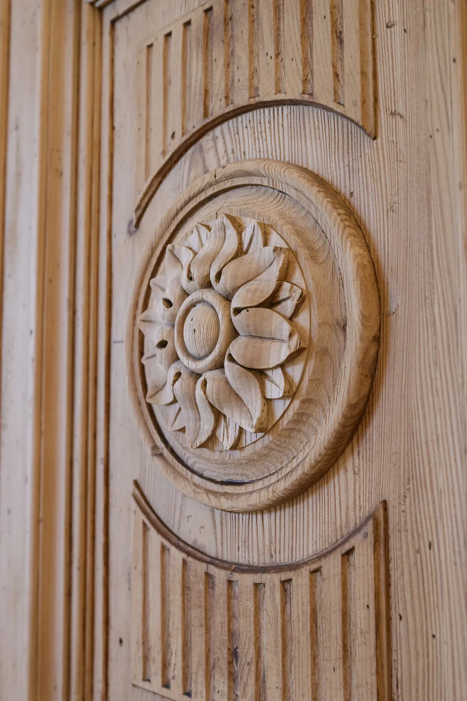 Detailaufnahme einer handgeschnitzten Rosettenornament-Verzierung auf der historischen Holzeingangstür des Steegwirt in Bad Goisern.