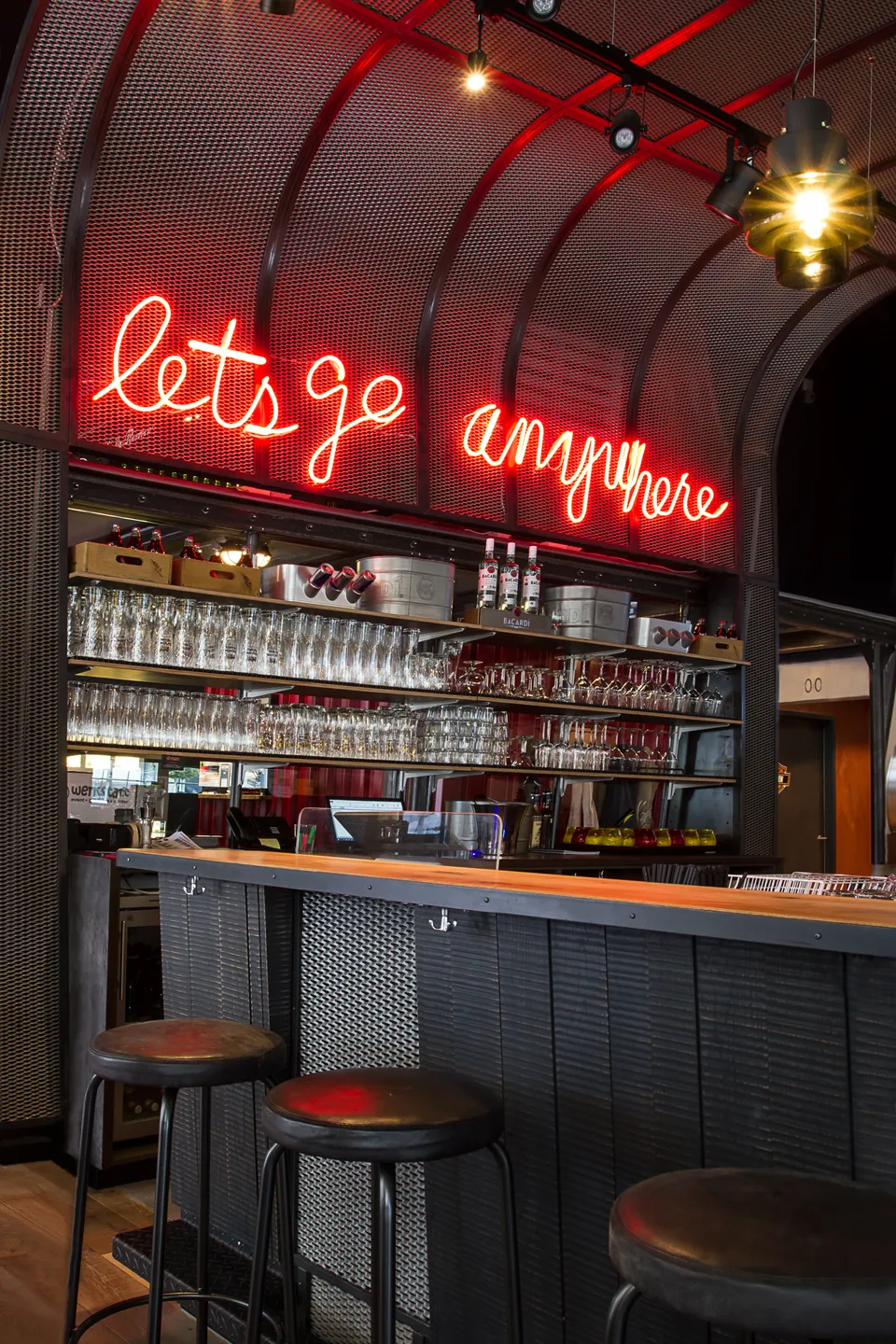 Bar der Werkstatt Kufstein mit rotem Neonschriftzug „lets go anywhere