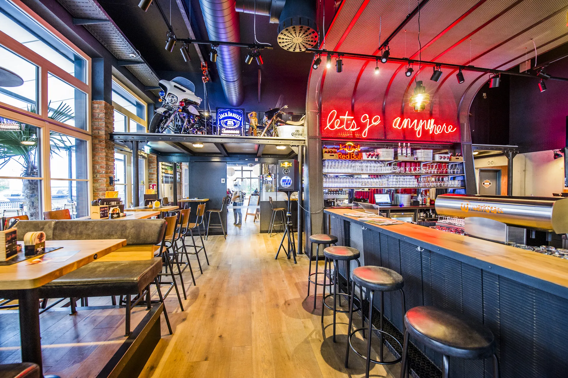 Gesamtansicht der Werkstatt Kufstein mit Bar, rotem Neonschriftzug „lets go anywhere