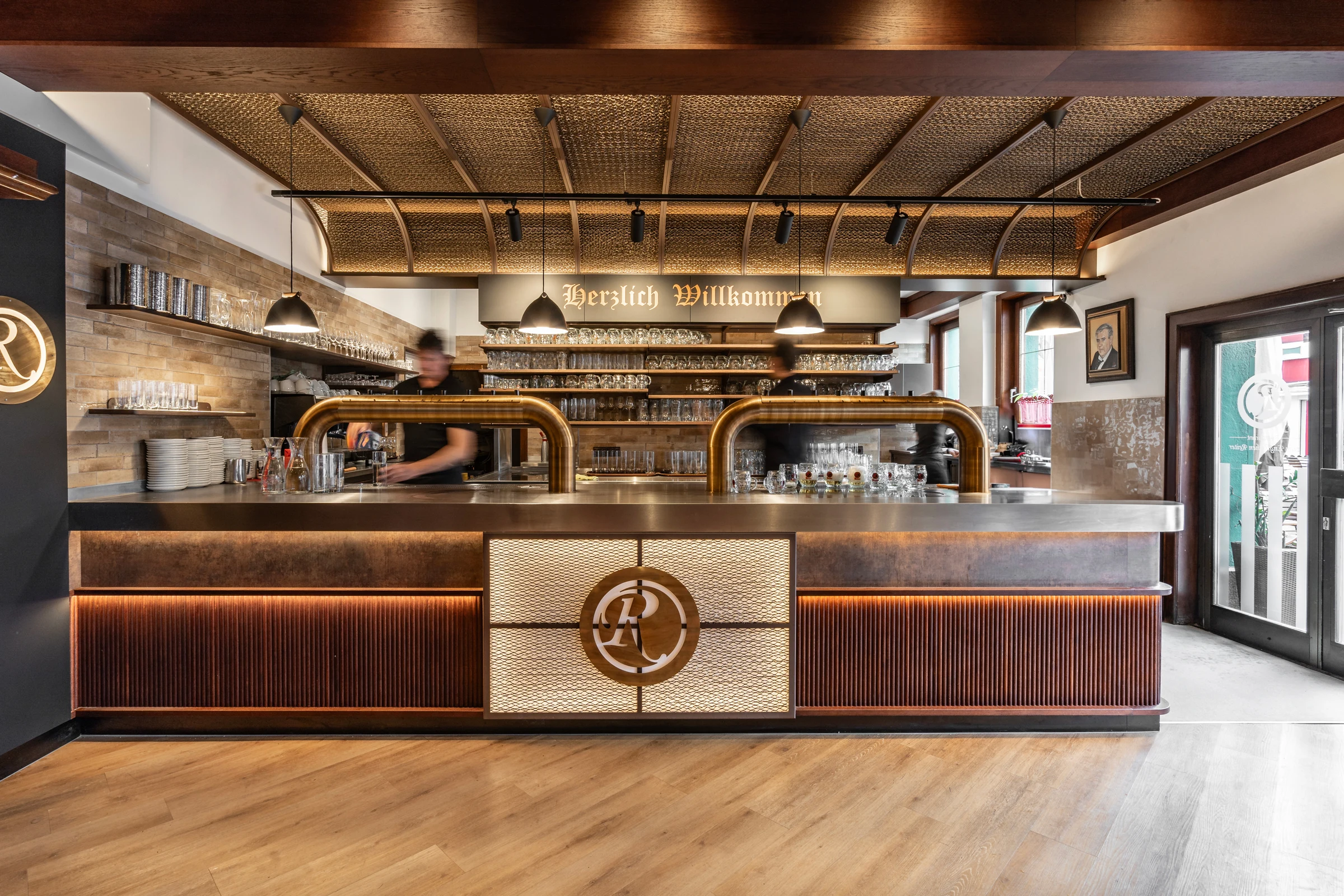 Bar des Restaurant Zum Englischen Reiter in Wien mit goldener Zapfanlage, beleuchtetem Messinglogo, Schriftzug „Herzlich Willkommen