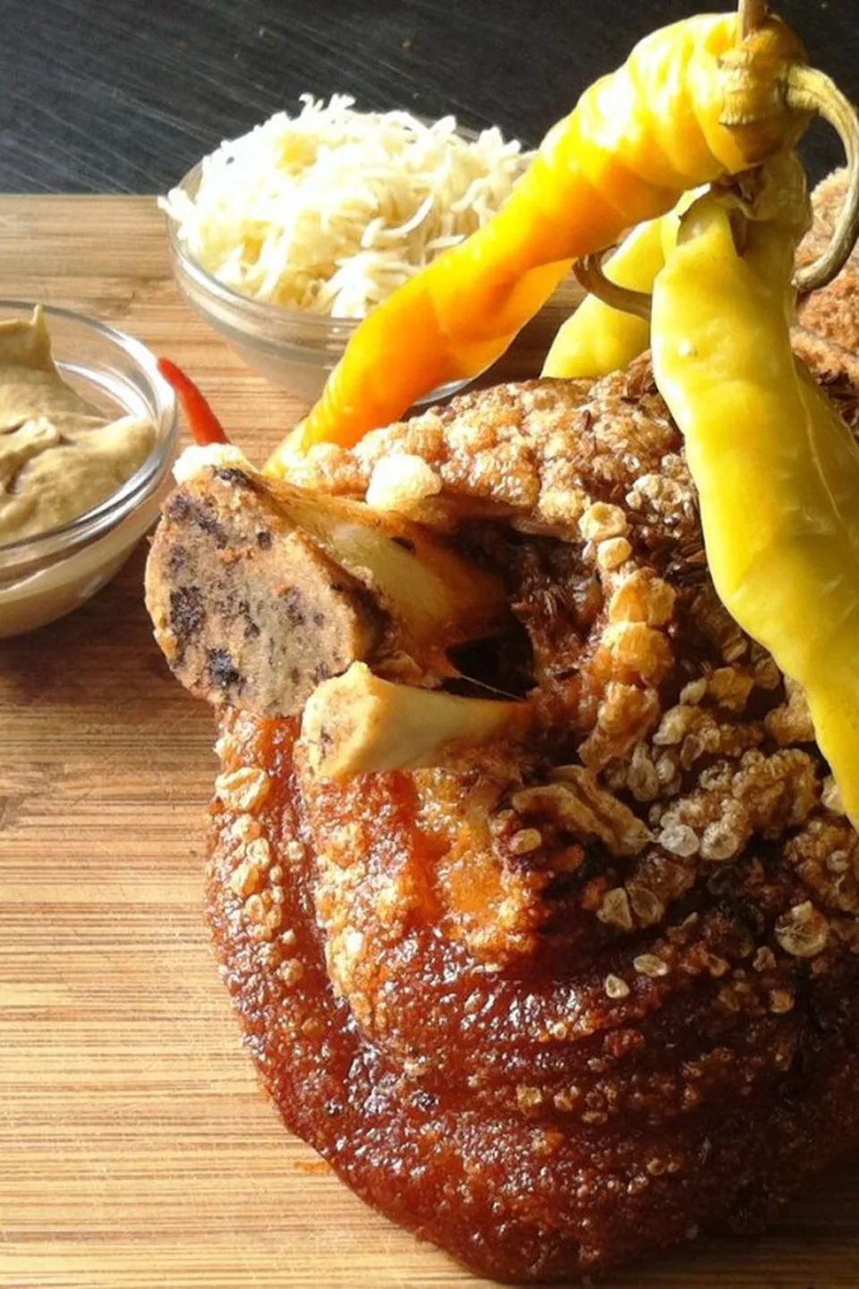Englische Stelze mit knuspriger Kruste, gelben Pfefferoni, Vollkornbrot, Senf und Kren auf Holzbrett – das Signature-Gericht des Restaurant Zum Englischen Reiter in Wien.