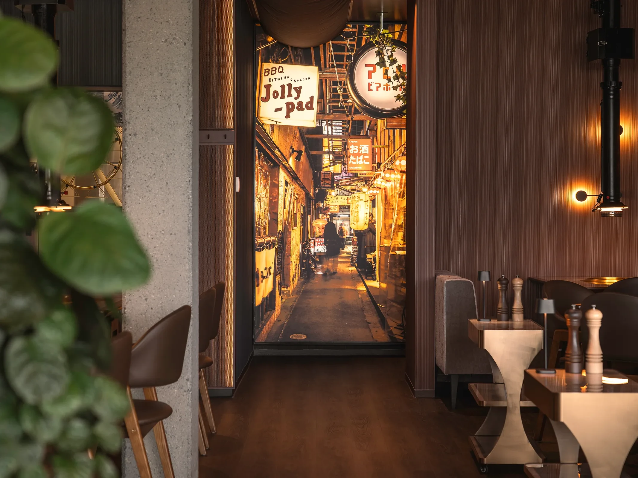 Elegant gestalteter Gastraum im japanischen Steakhouse Akiko in Bürs mit Grilltischen, Hängeleuchten und Blick in den beleuchteten Gastro-Gang.