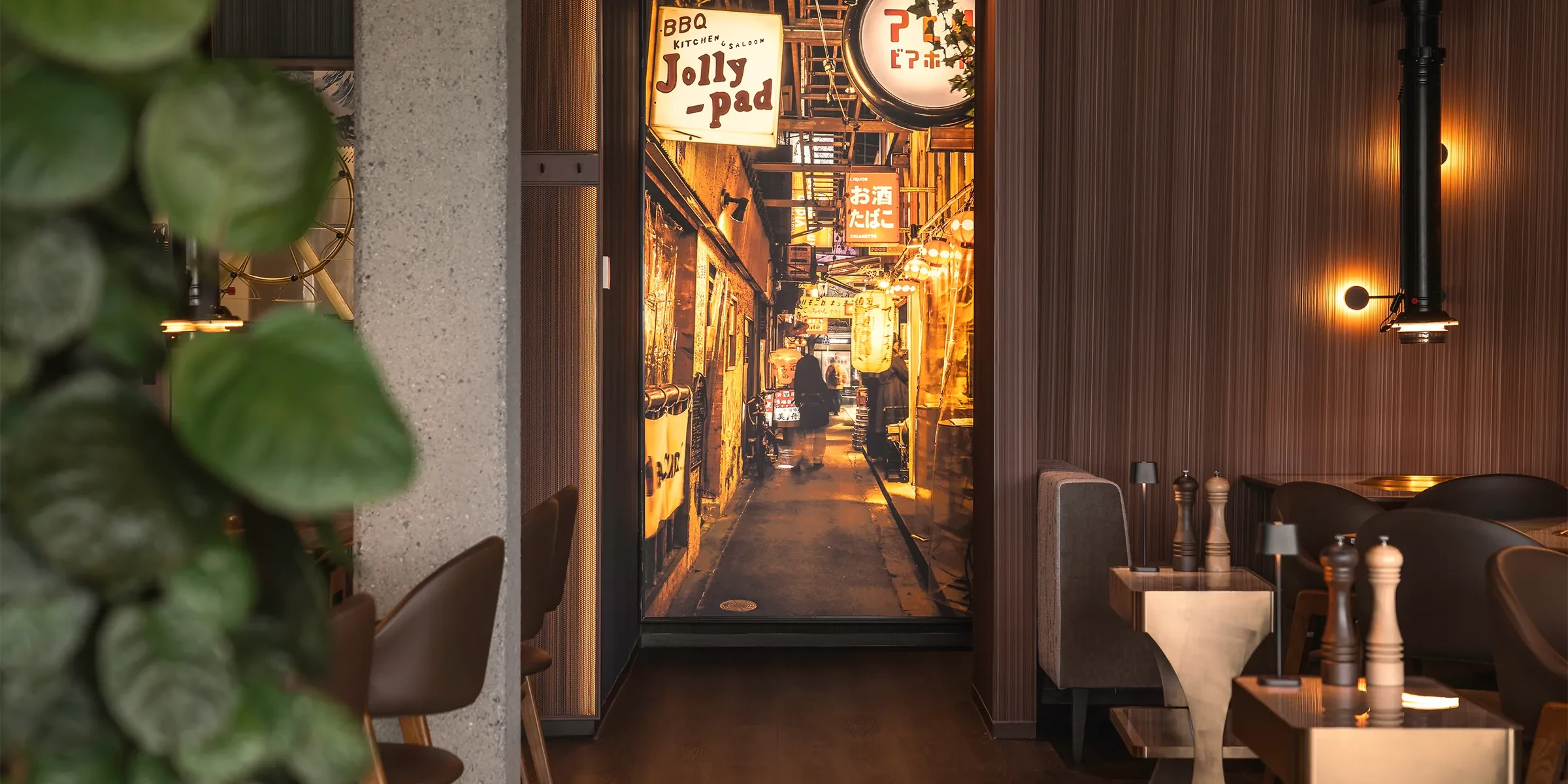 Elegant gestalteter Gastraum im japanischen Steakhouse Akiko in Bürs mit Grilltischen, Hängeleuchten und Blick in den beleuchteten Gastro-Gang.