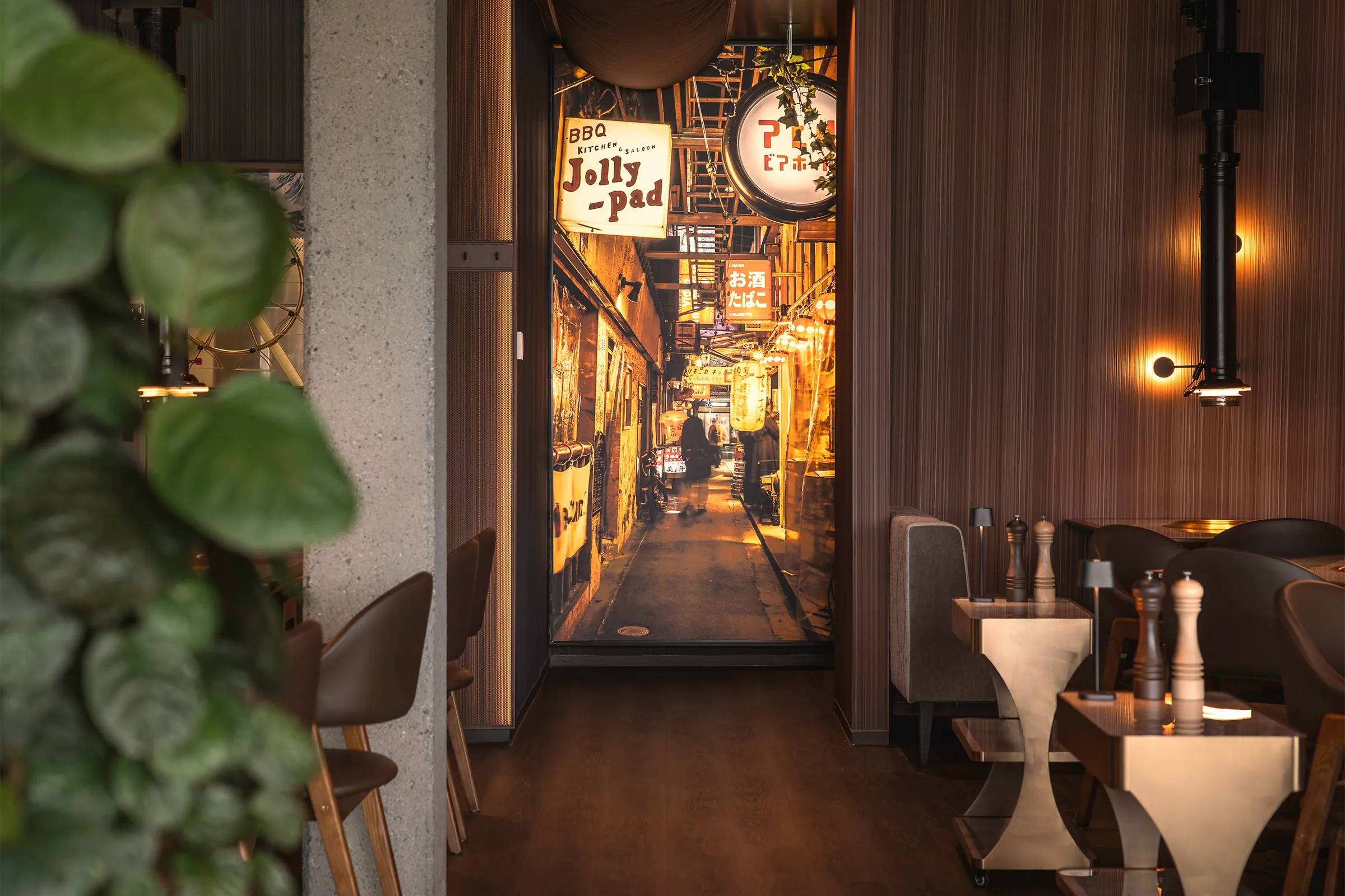 Elegant gestalteter Gastraum im japanischen Steakhouse Akiko in Bürs mit Grilltischen, Hängeleuchten und Blick in den beleuchteten Gastro-Gang.