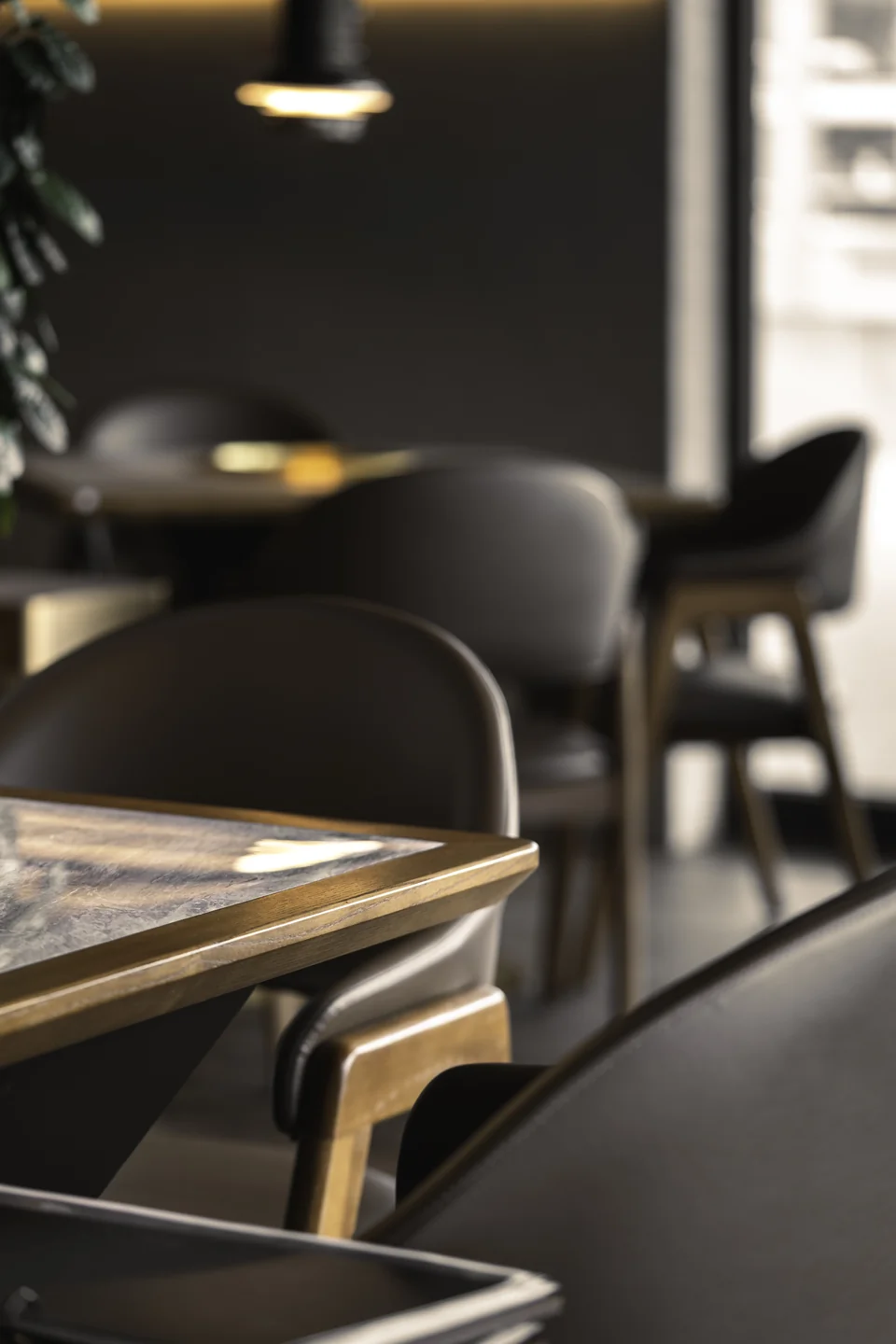 Stimmungsvolles Tischdetail mit dunklen Polsterstühlen und Golddetails im Akiko Bürs.