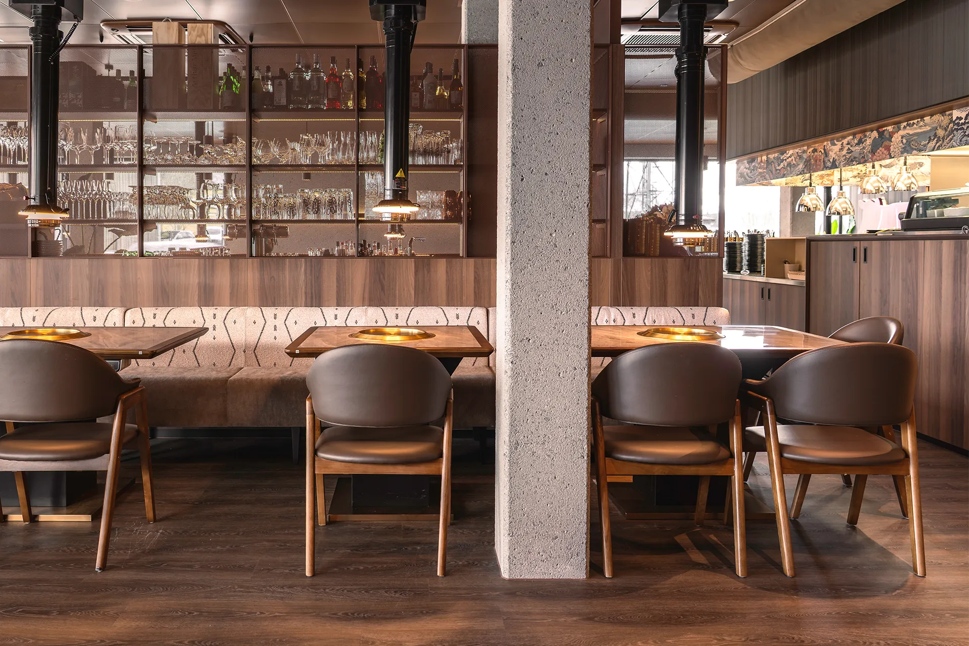 Sitzbereich mit Eckbank und Sichtbetonsäule vor beleuchtetem Bar-Regal im Akiko Bürs.