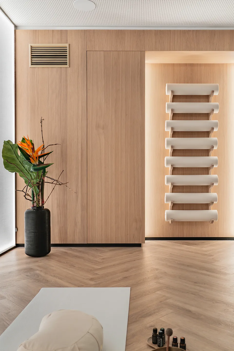 Meditationsbolster und Kissen auf einer Yogamatte im Breath-in Room der Biogena Plaza Wien, im Hintergrund eine Strelitzie in weichem Licht.